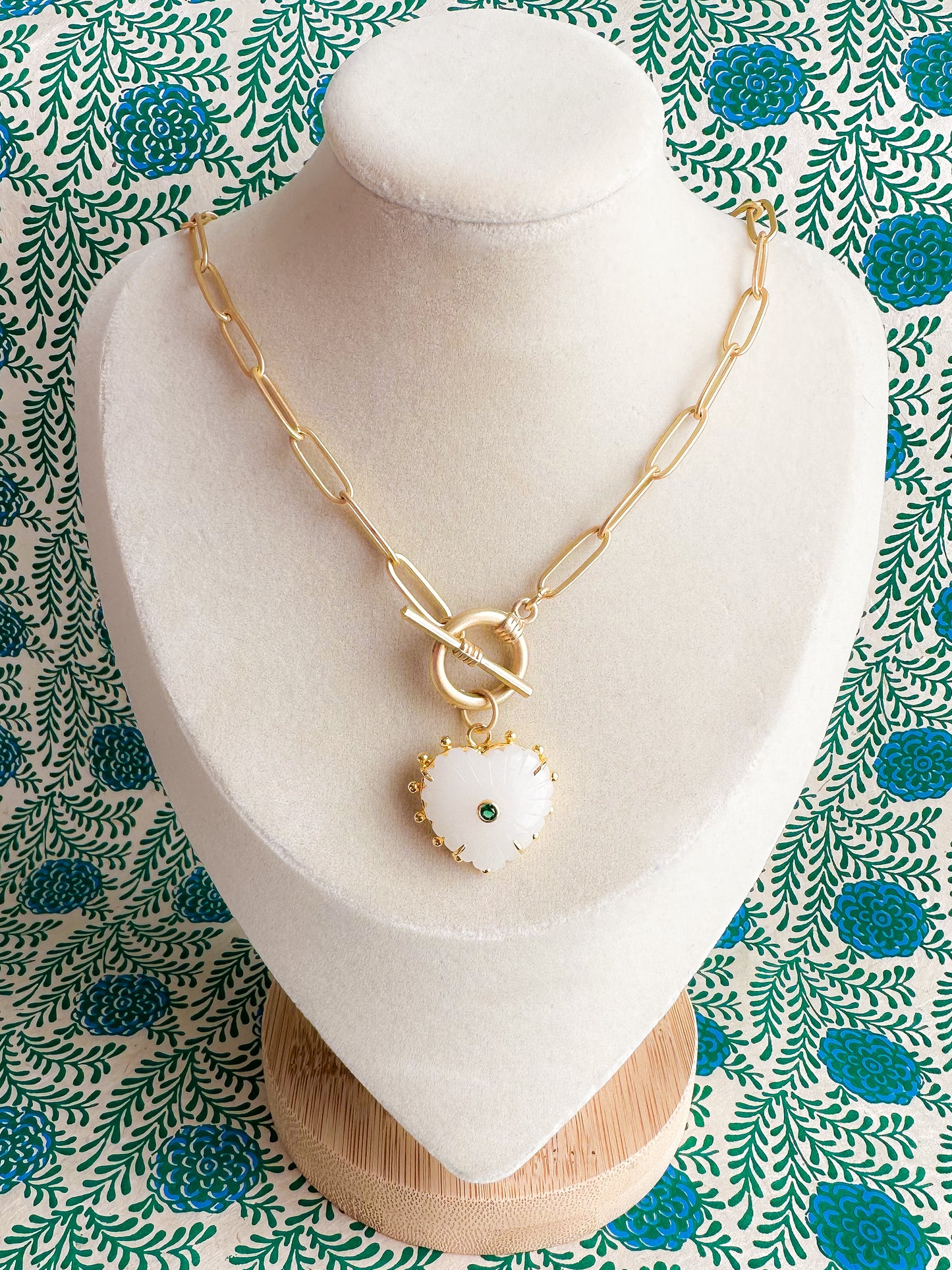 Gold paper clip necklace with a toggle clasp and heart-shaped carved chalcedony pendant.