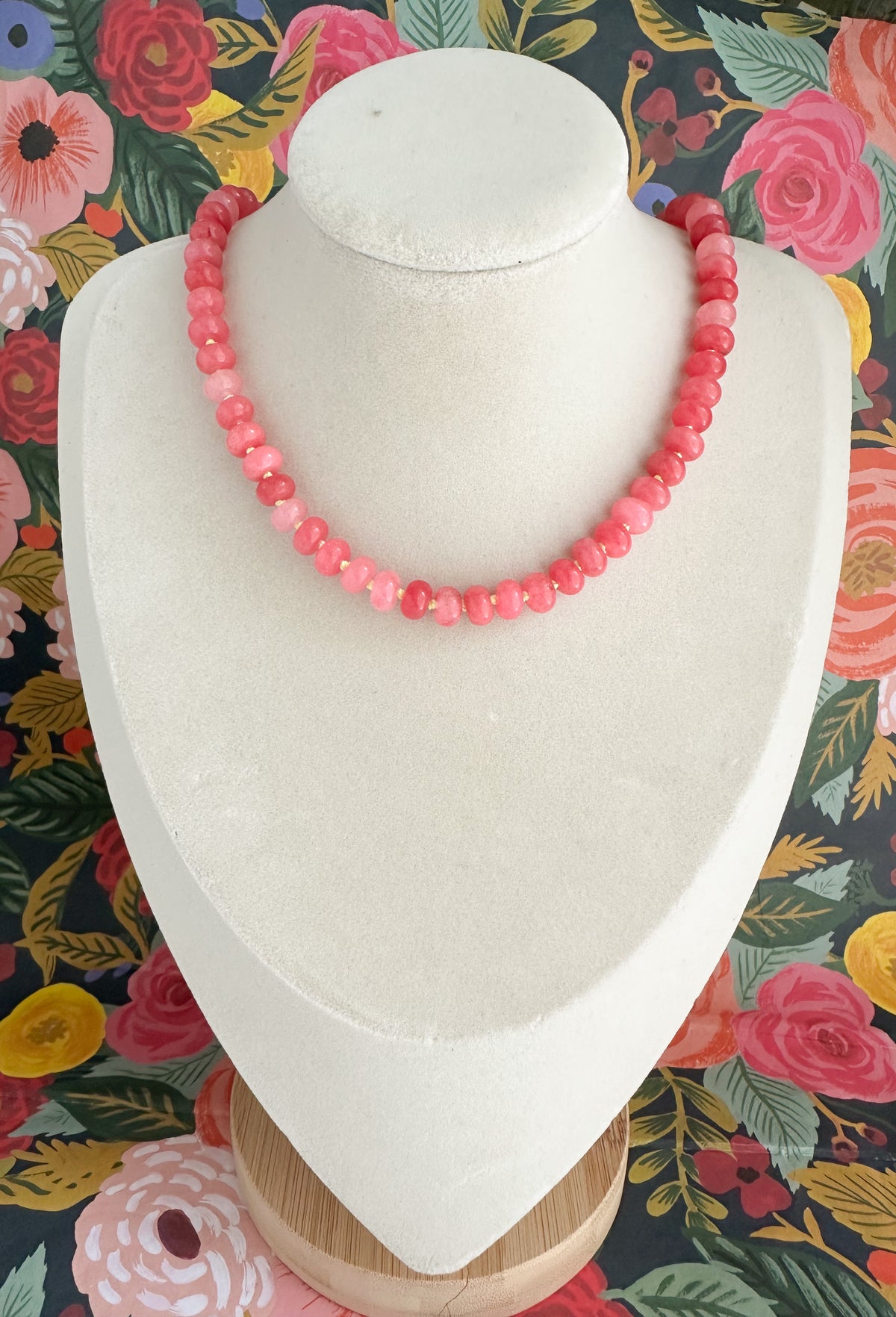 Orchid Pink Jade necklace displayed on a white jewelry bust with a colorful floral background.