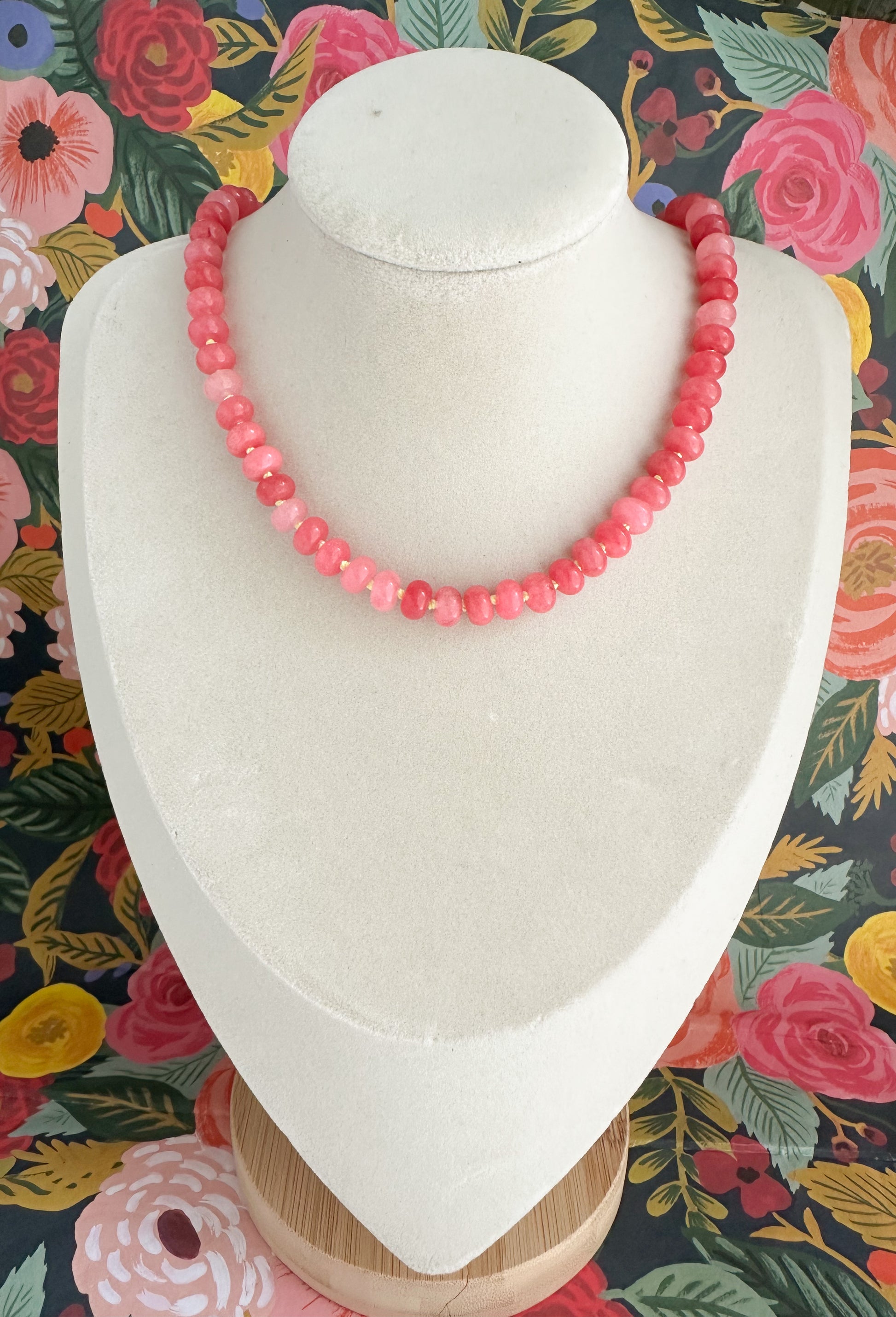 Orchid Pink Jade necklace displayed on a white jewelry bust with a colorful floral background.